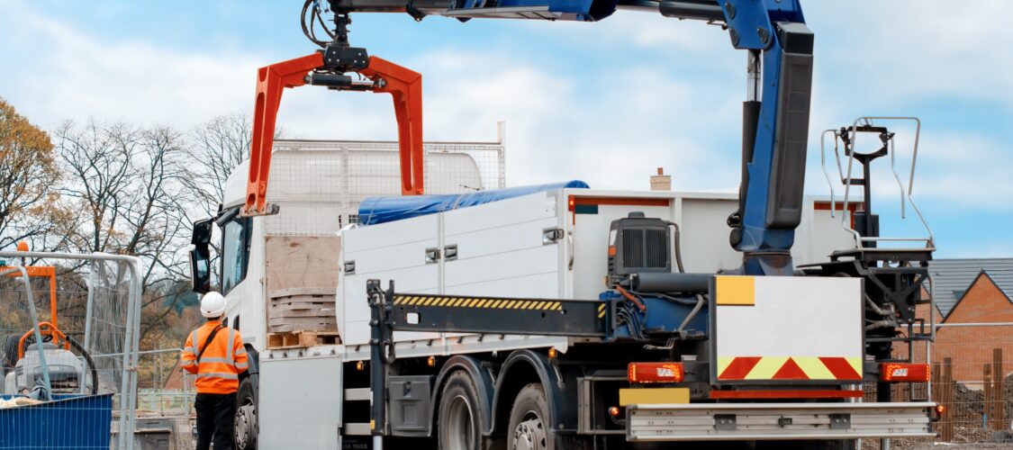 flatbed hiab crane lorry with brick grab attachment deliver materials on construction site and offloading them
