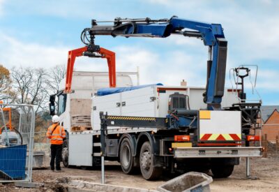 flatbed hiab crane lorry with brick grab attachment deliver materials on construction site and offloading them