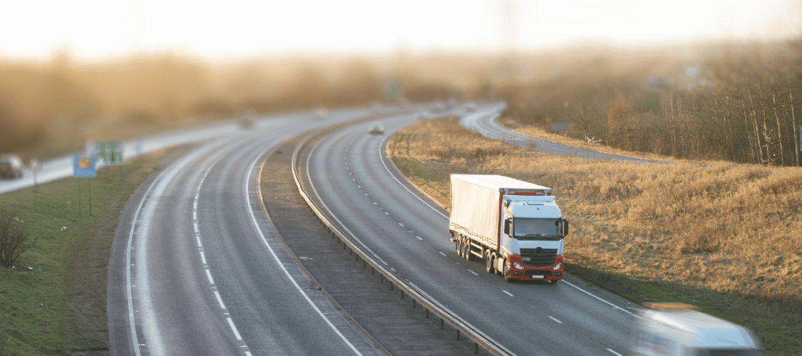 a uk main road seen at a distance with cars, a van and a hgv.